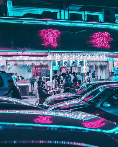 A photo of a neon lit Chinese store sign along a busy street in Shenzhen, China
