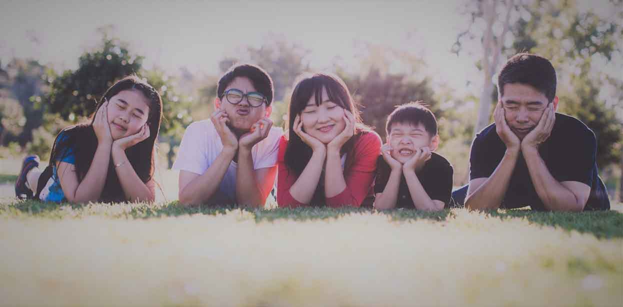 A photo of an Asian family lying on a field of grass